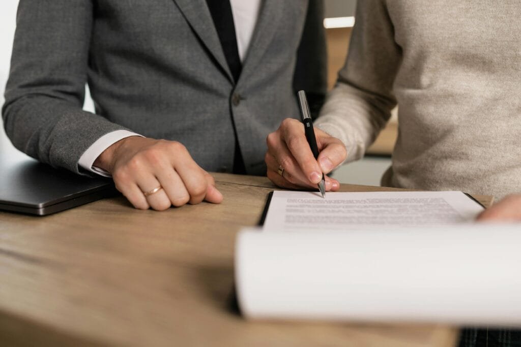 Finalizing the design of an affiliate disclosure document: a close-up of a person signing the paper at a wooden desk