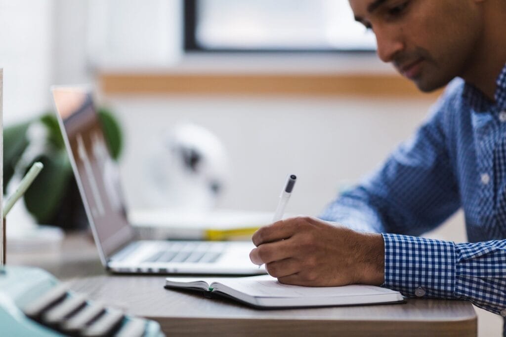 About Us Man writing in front of laptop: our unbreakable editorial standards